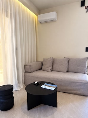 Ein modernes Wohnzimmer mit einer Couch, einem schwarzen Couchtisch und einer Fernbedienung.