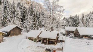 Ein verschneites Dorf mit Holzhütten, Bergen im Hintergrund und klarem Himmel.