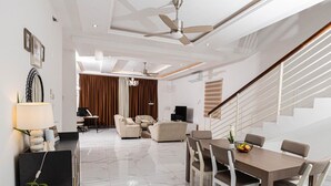 Ein modernes Wohnzimmer mit Essbereich, einer Treppe und einem Deckenventilator.