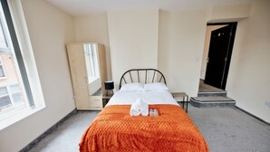 Una habitación de hotel con una cama, un armario, un espejo y una puerta.