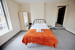 Ein Hotelzimmer mit einem Bett, einem Kleiderschrank, einem Spiegel und einer Tür.