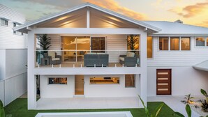A modern two-story house with a balcony, large windows, and a well-maintained lawn. - Bliss On The Avenue - Refined living (Burleigh Waters)