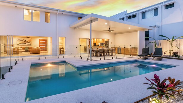 A modern house with a swimming pool, a dining area, and a living room with a sofa and a TV. - Bliss On The Avenue - Refined living (Burleigh Waters)