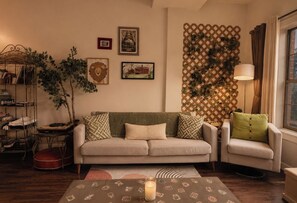 Uma sala de estar com sofá, poltrona e mesa de centro com uma vela.