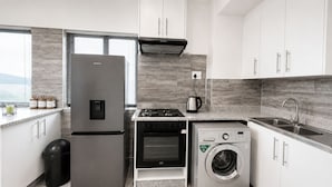 Una cocina compacta equipada con refrigerador, horno, microondas y lavadora.
