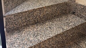 A set of granite stairs with a potted plant on the landing.