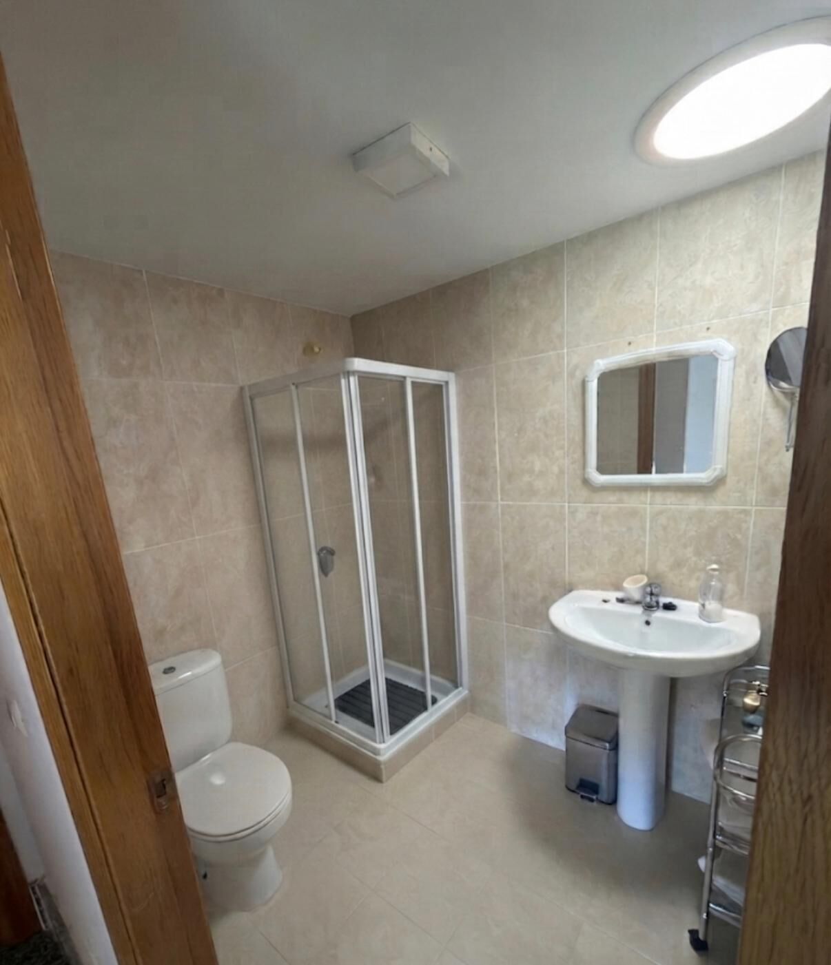 A bathroom with a shower, toilet, sink, and a mirror.