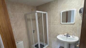 A bathroom with a shower, toilet, sink, and a mirror.