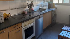A kitchen with wooden cabinets, a stove, a dishwasher, and a washing machine.