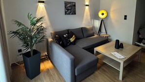 Ein modernes Wohnzimmer mit einem grauen Sofa, einem Holztisch, einer Stehlampe und einem Blumentopf.