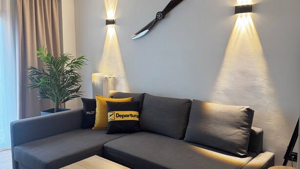 Ein modernes Wohnzimmer mit einem Ecksofa, einem Couchtisch und wandmontierten Leuchten.
