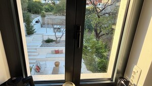 Una habitación con un ventanal grande, una silla negra, dos cubos de basura y una regleta.