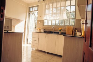 Cozinha com armários de madeira, bancada e janela com vista para árvores.