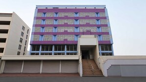 Monikerroksinen rakennus, jonka julkisivu on violetti, siinä on suuret ikkunat ja keskeisellä paikalla sijaitseva portaikko, joka johtaa sisäänkäyntiin.