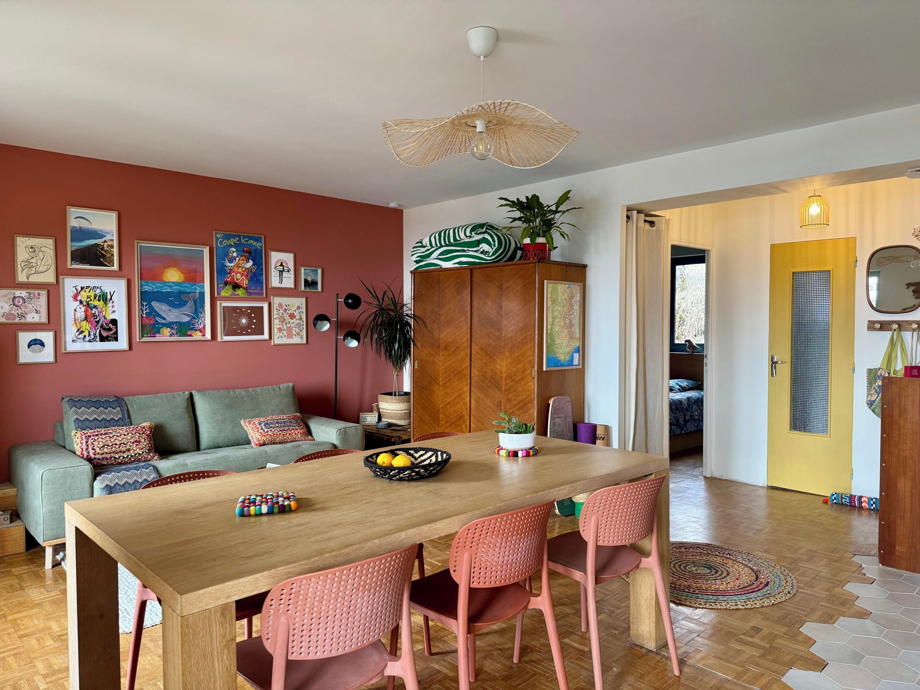 A dining area with a wooden table, pink chairs, and a variety of wall art.