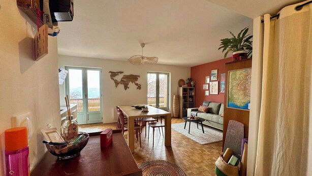 A spacious living area with a dining table, sofa, and a world map on the wall. - "SIGI" Cozy apartment at the foot of the Ceüse cliff (Sigoyer)