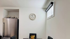 Zona pranzo con tavolo, sedie, orologio e frigorifero.
