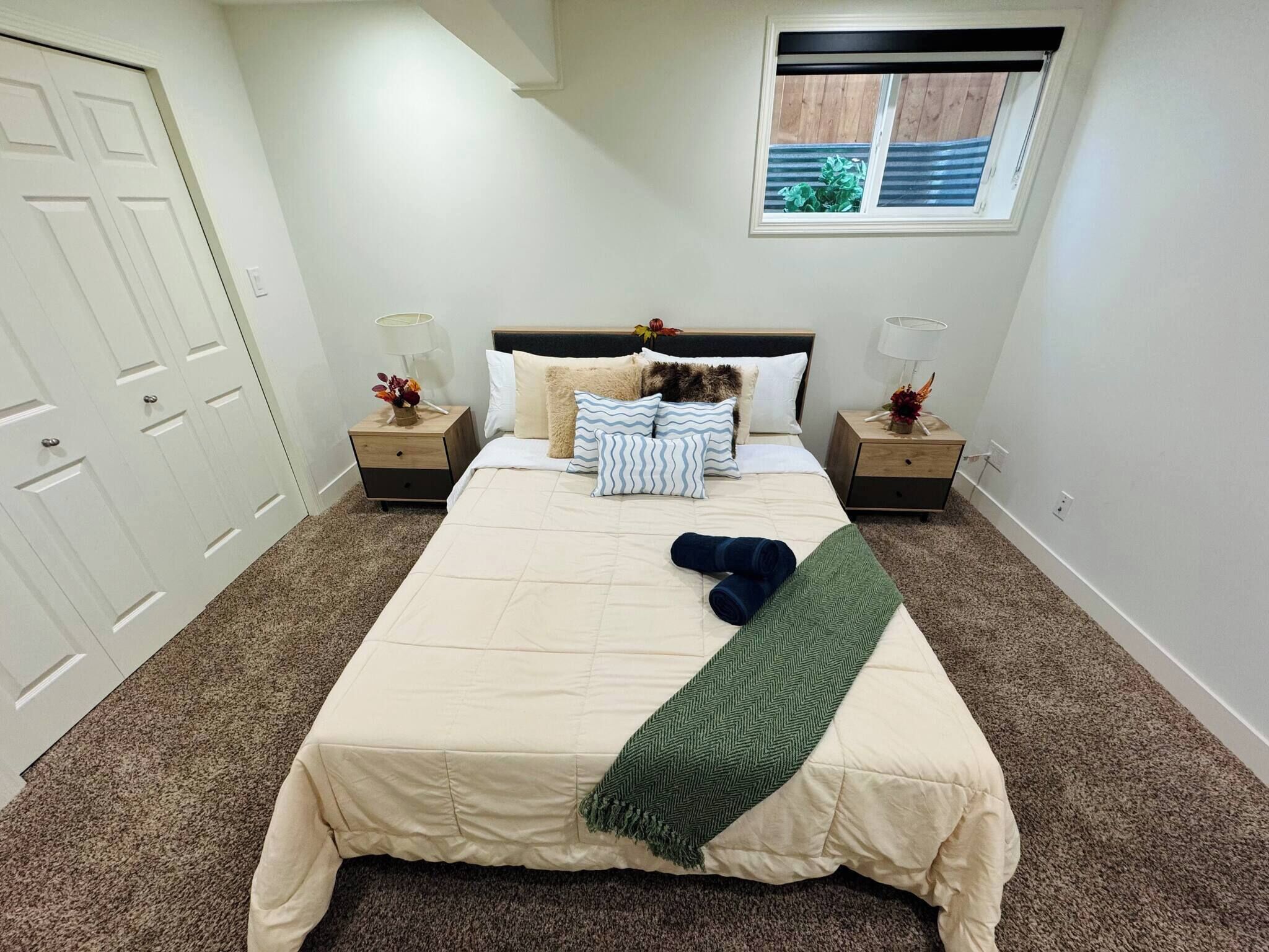 Ein Schlafzimmer mit einem großen Bett, zwei Nachttischen, einem Fenster und einer Tür.