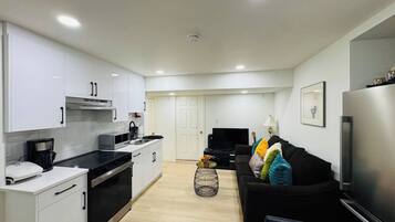 A modern kitchen with white cabinets, a black countertop, and a stainless steel refrigerator.