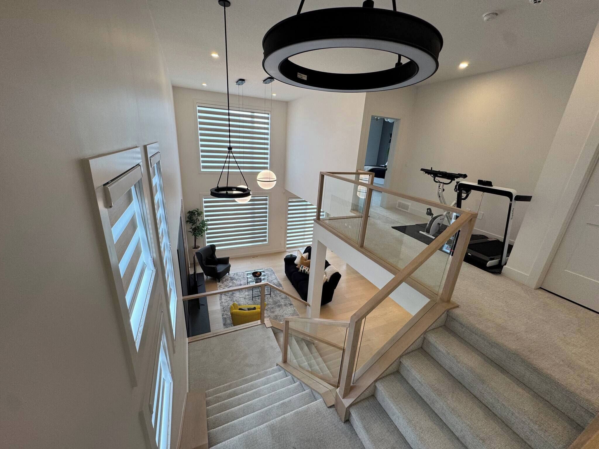 Un interior moderno con una escalera, una cinta de correr y una lámpara colgante.