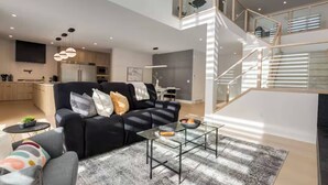 A modern living room with a sofa, coffee table, and a staircase leading to an upper level.