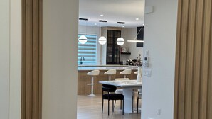 A modern kitchen with a dining area, wooden flooring, and pendant lighting.