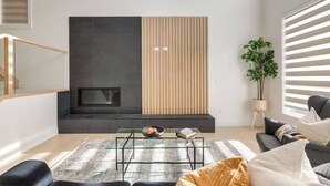 A modern living room with a fireplace, a sofa, a coffee table, and a potted plant.