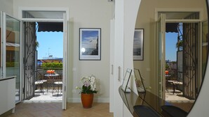 Un pasillo con vista a un patio exterior, un cuadro en la pared y una planta en maceta.