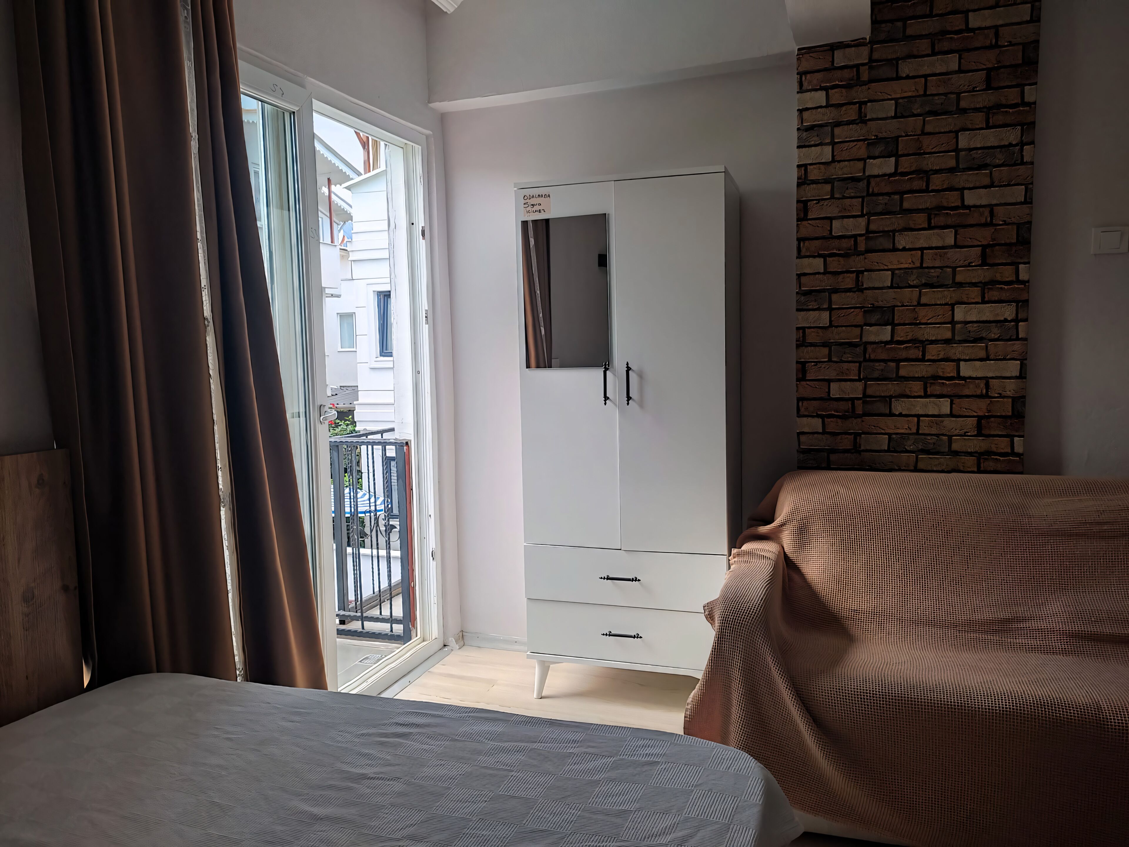 Un dormitorio con cama, armario y vista al balcón exterior.