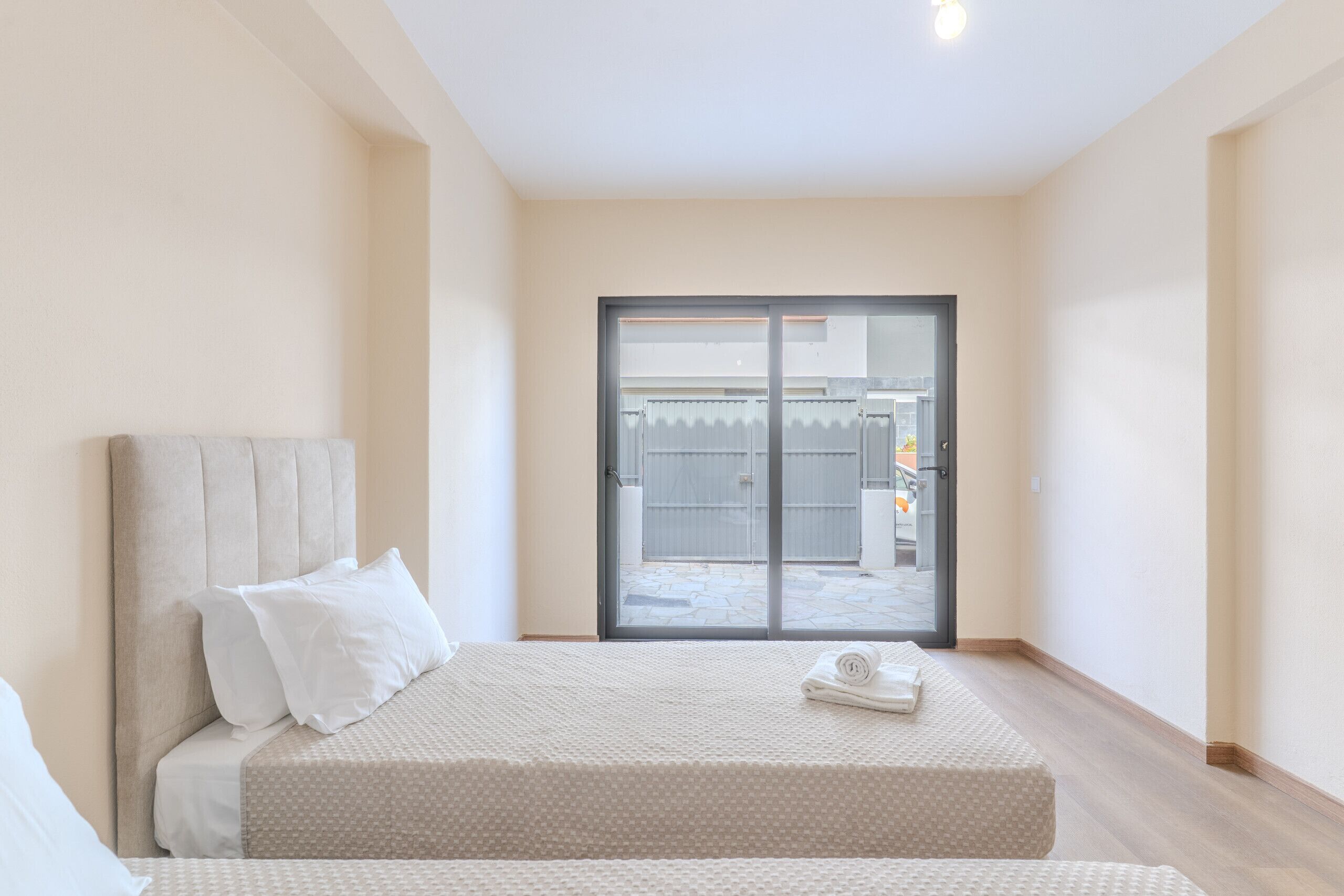 Een slaapkamer met een bed, kussens, een raam en uitzicht op het omliggende landschap.