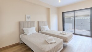 Camera d'albergo con due letti, una porta scorrevole in vetro che dà sull'esterno e un'opera d'arte a forma di cuore sulla parete.