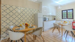 Una cucina moderna con mobili bianchi, un tavolo da pranzo con sedie e un angolo per la colazione.