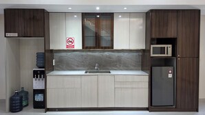 A modern kitchen with a built-in microwave, a water dispenser, and a refrigerator. - Unika Coliving Vibes Syariah (Pekanbaru)