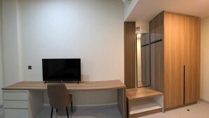 A modern room with a desk, chair, television, and wardrobe. - Unika Coliving Vibes Syariah (Pekanbaru)