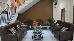 A modern living room with two sofas, a coffee table, and a staircase. - Unika Coliving Vibes Syariah (Pekanbaru)