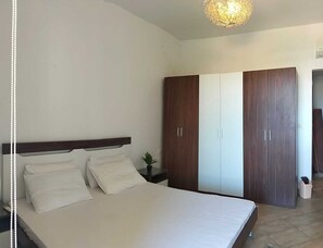 A bedroom with a bed, a wardrobe, and a nightstand. - Delightful 2-bedroom chalet with Sea View in Amwaj (Marsa Matrouh Governorate)