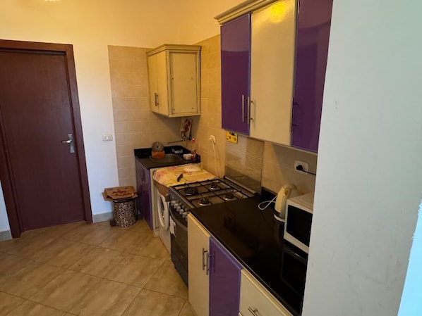 A compact kitchen with a stove, sink, and cabinets.