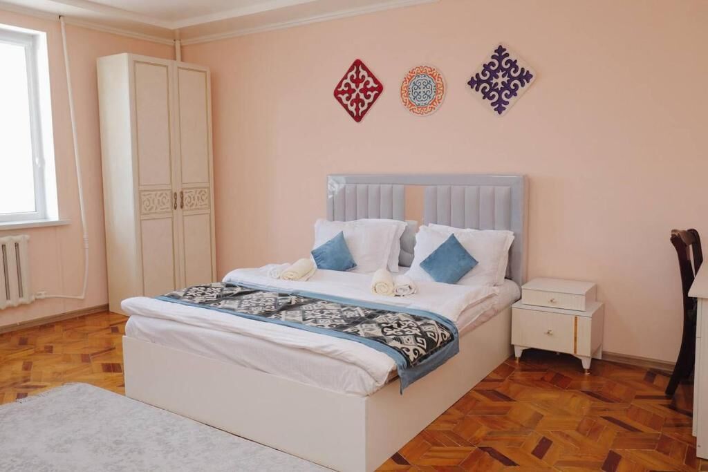 A bedroom with a bed, nightstand, wardrobe, and decorative wall art.