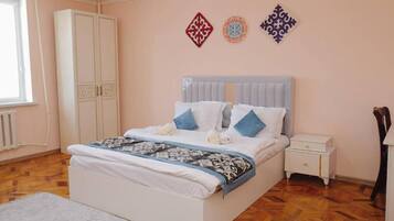 A bedroom with a bed, nightstand, wardrobe, and decorative wall art.