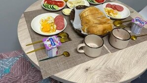 Una mesa redonda con platos de comida, una hogaza de pan y una taza.
