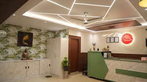 A reception area with a marble reception desk, a Buddha statue, a green counter, and a ceiling with geometric lighting. - I Cloud Elite Suites (Bengaluru)