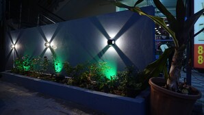 A building exterior with a blue wall, three spherical lights, and a planter with plants. - I Cloud Elite Suites (Bengaluru)