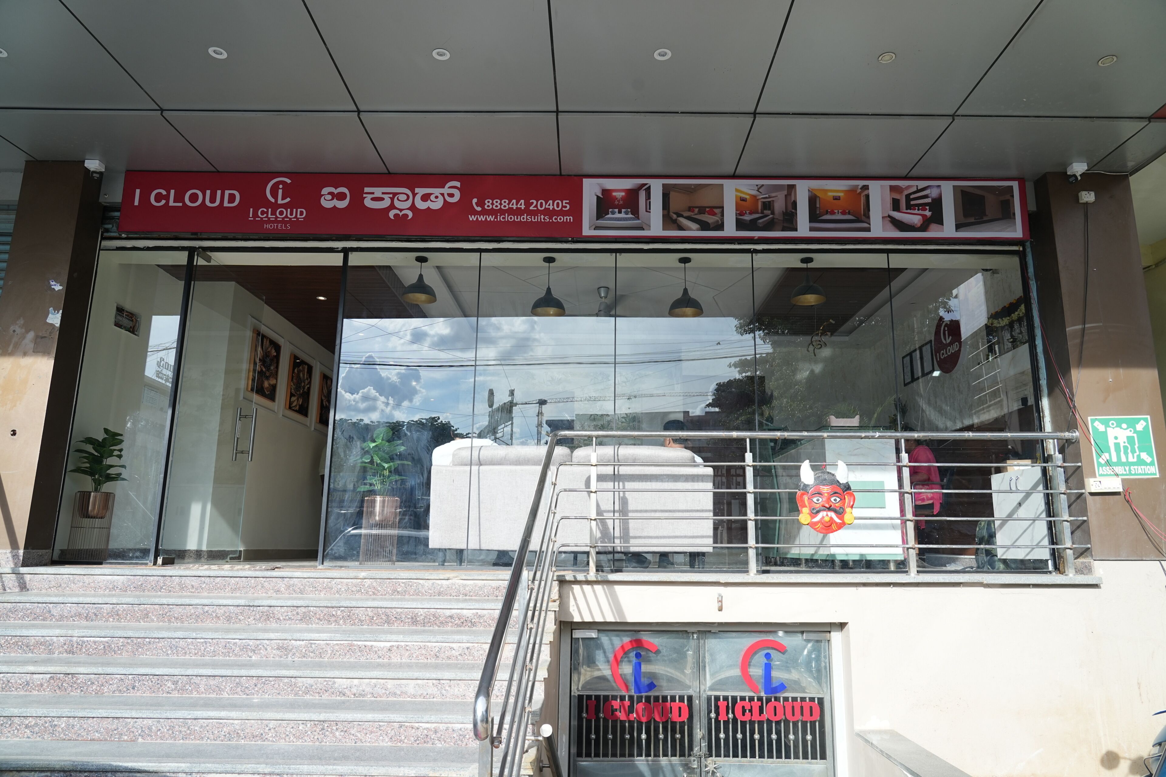 A hotel entrance with a signboard, glass doors, and a staircase leading inside.