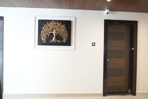 Un pasillo con una obra de arte de un árbol, una puerta de madera oscura y una pared de color claro.