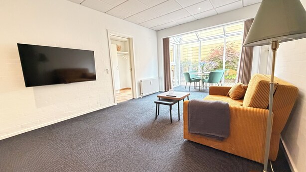 Un salon moderne avec un téléviseur à écran plat, un canapé, une table basse et un lampadaire.