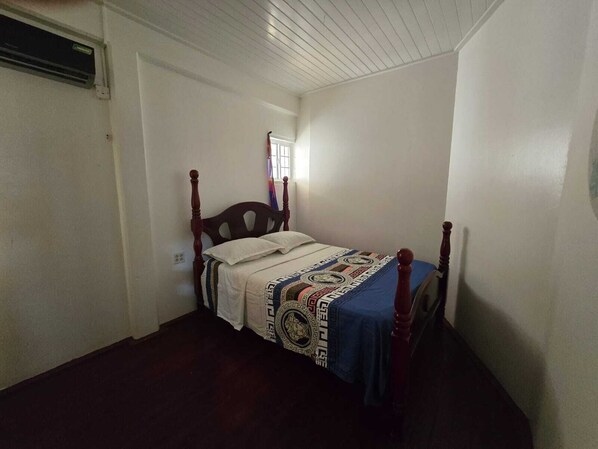 A bedroom with a wooden bed, white walls, and a window with blinds.