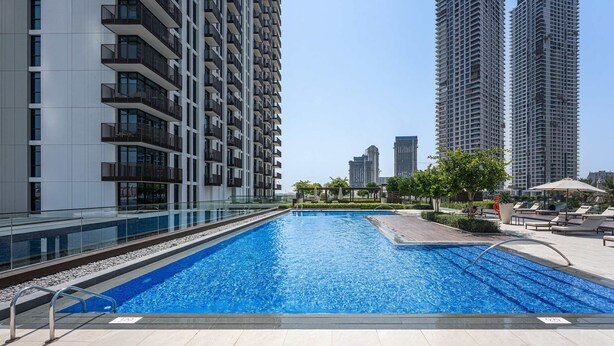 A swimming pool with a glass railing, surrounded by high-rise buildings. - Free Housekeeping Visits During Your Stay - Stayshort - 1 Bedroom Escape in Dubai Creek Harbour That Sleeps 2 (Dubai)