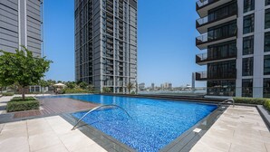 A rooftop swimming pool with a clear view of the city skyline, surrounded by modern buildings. - Free Housekeeping Visits During Your Stay - Stayshort - 1 Bedroom Escape in Dubai Creek Harbour That Sleeps 2 (Dubai)