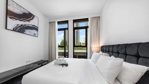 A hotel room with a large bed, a headboard, a window with curtains, and a wall-mounted artwork. - Free Housekeeping Visits During Your Stay - Stayshort - 1 Bedroom Escape in Dubai Creek Harbour That Sleeps 2 (Dubai)