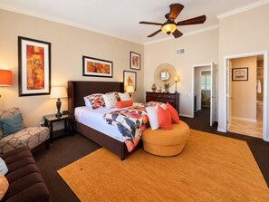 A bedroom with a bed, a nightstand, a lamp, a ceiling fan, and artwork on the walls. - 2BR Condo | Pool & Hot Tub | Downtown Palm Springs | Mountain Views (Palm Springs)